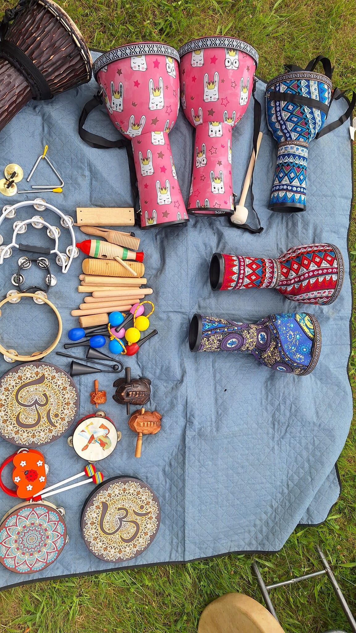 Barevné bubny a rytmické nástroje rozložené na dece na trávě